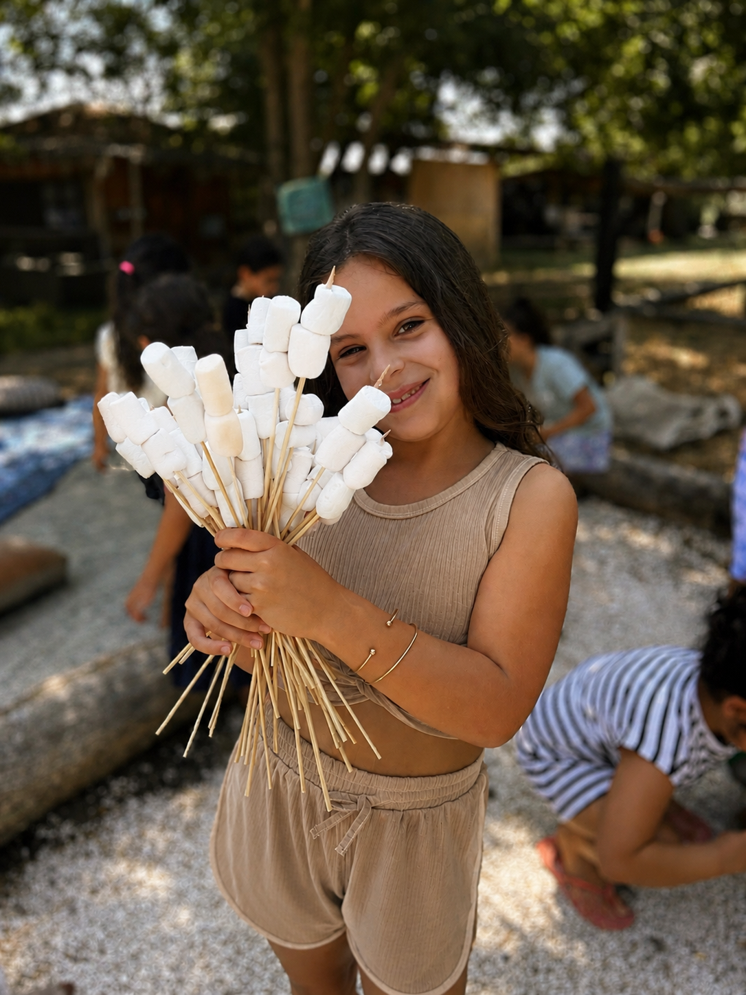 ילדה מחייכת עם שיפודי מרשמלו בפעילות FlowerZ בטבע